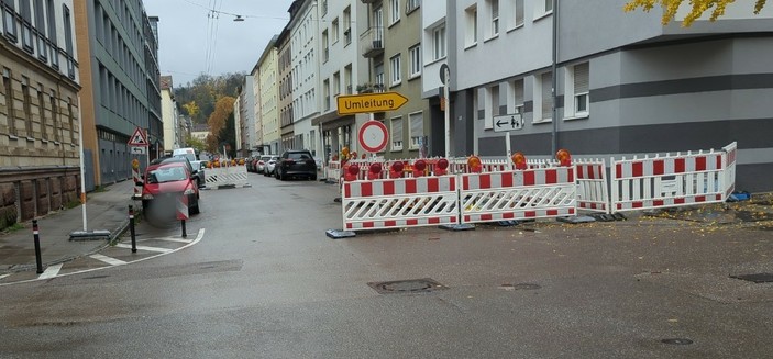 eine komplett geöffnete Baustellen-Absperrung mit falsch parkenden Autos darin