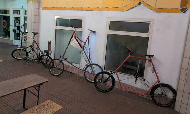 die drei Tallbikes Talldem, Weitblick und Hexabike stehen an einer Wand gelehnt.